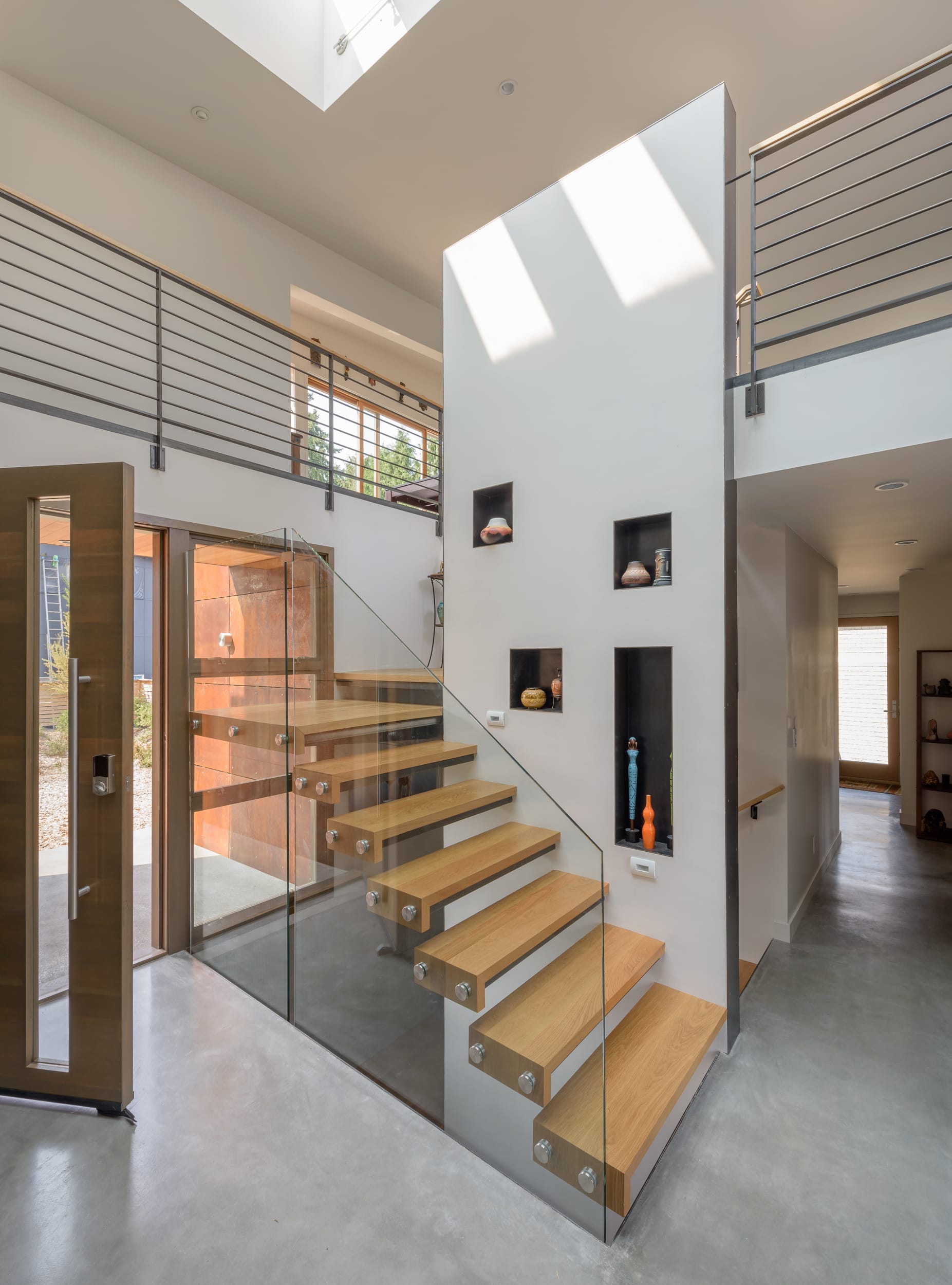 A modern staircase in a house with glass railings.