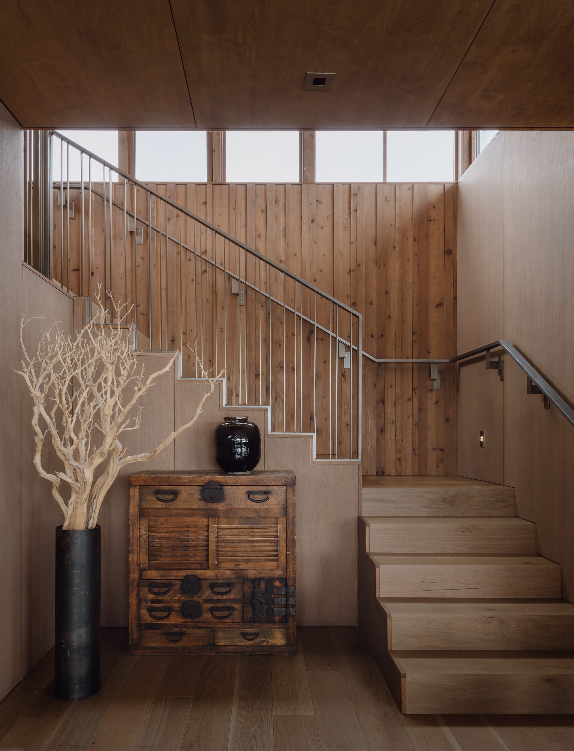 A modern home entryway featuring wooden stairs and a wooden planter, expertly crafted by a carpenter.
