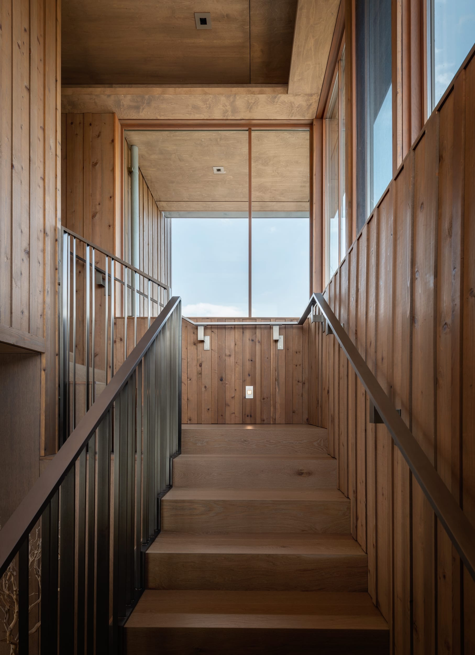 A wooden staircase leading up to a glass wall, expertly crafted by a skilled carpenter.