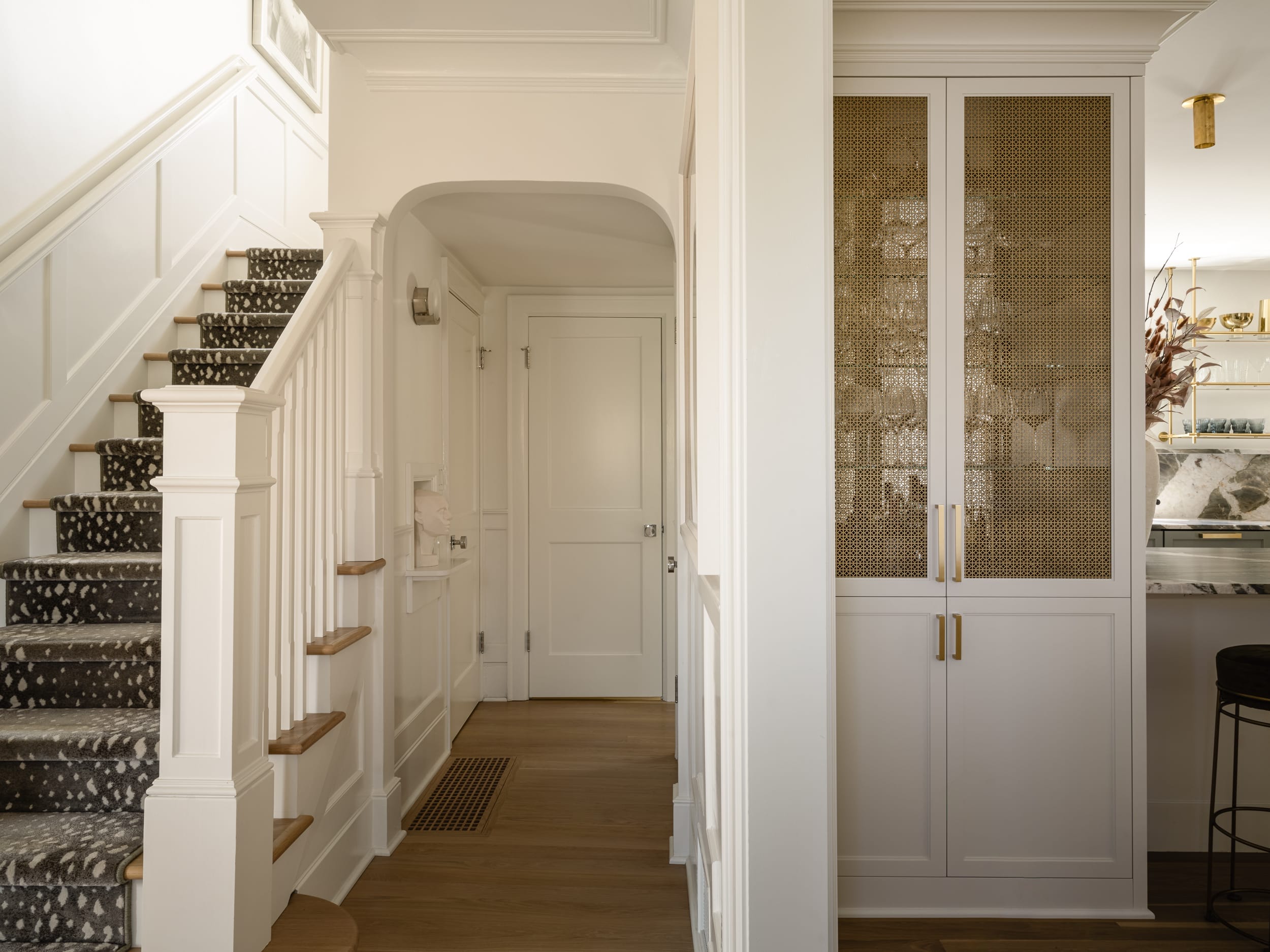 A hallway with white walls and stairs.