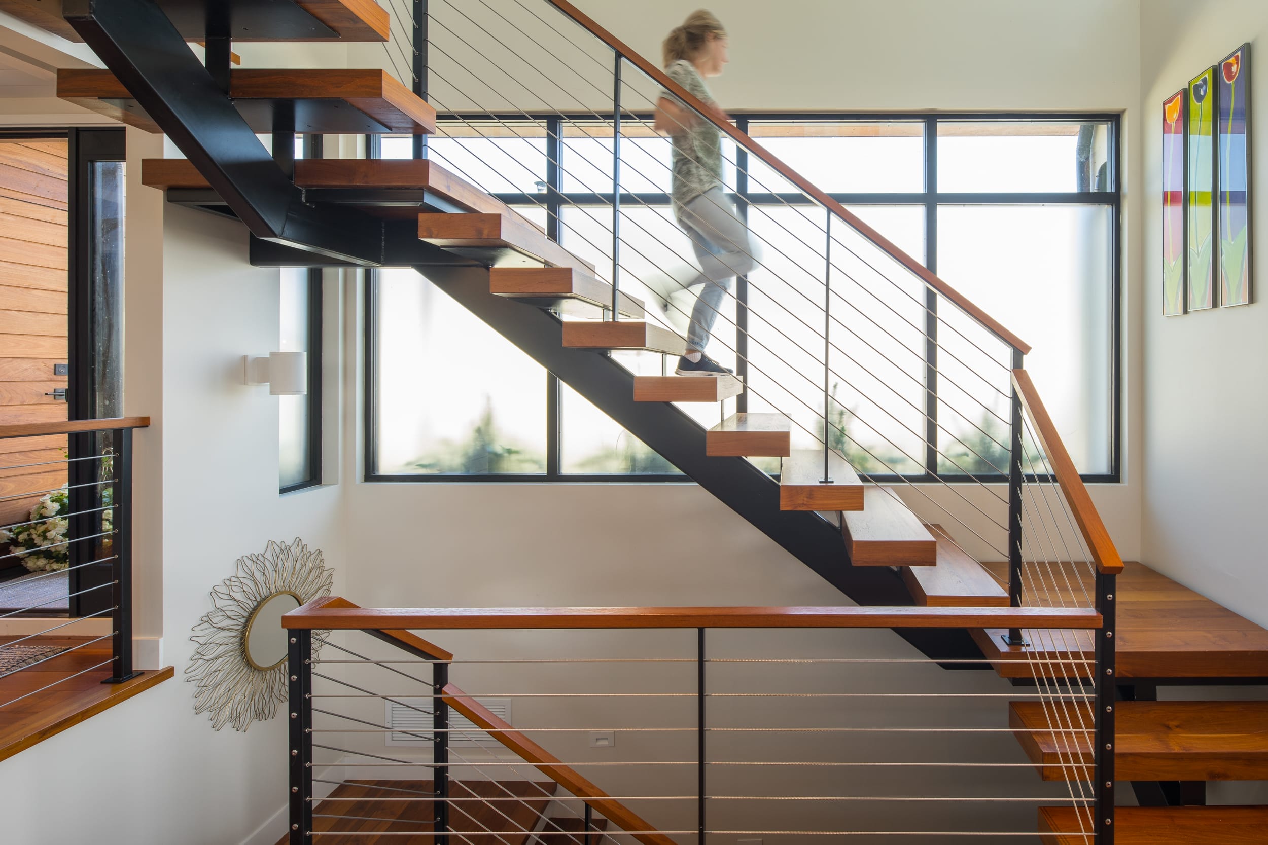 A woman is walking up a staircase in a Modern Home.