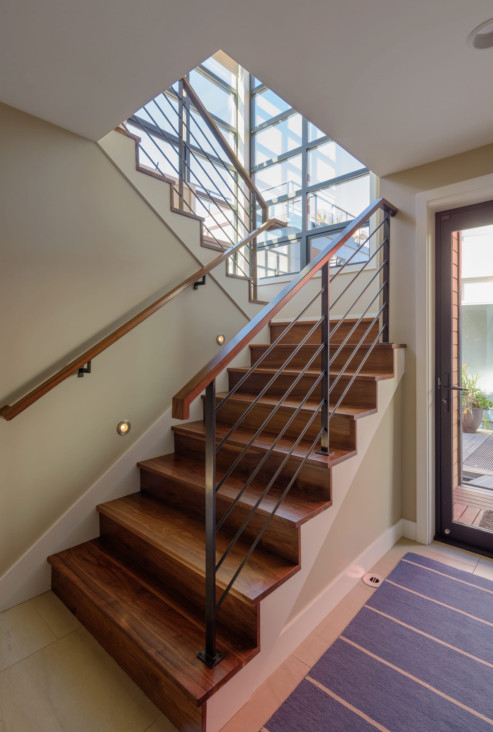 A modern staircase in a home with a glass door.