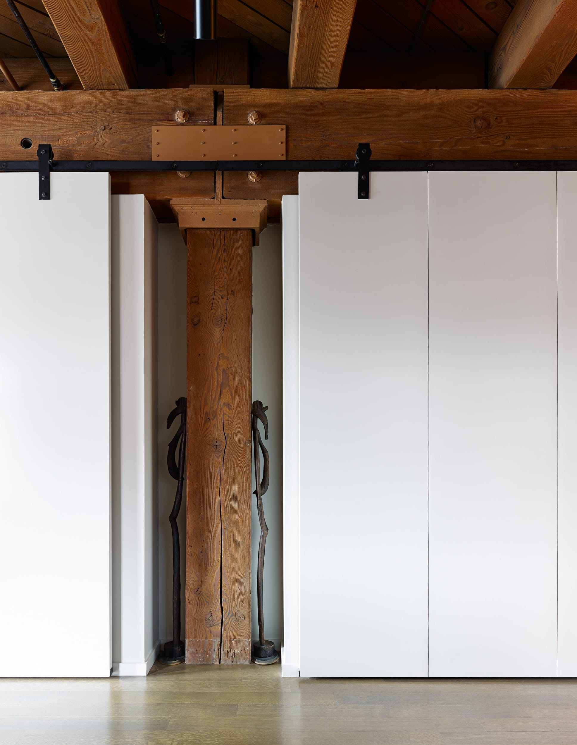 A white sliding door in a room with wooden beams.