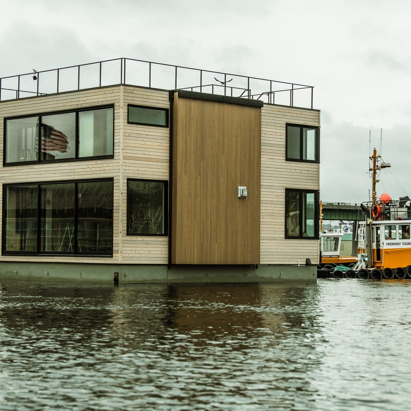 A Seattle floating home with a boat behind it, built by an experienced floating home builder.