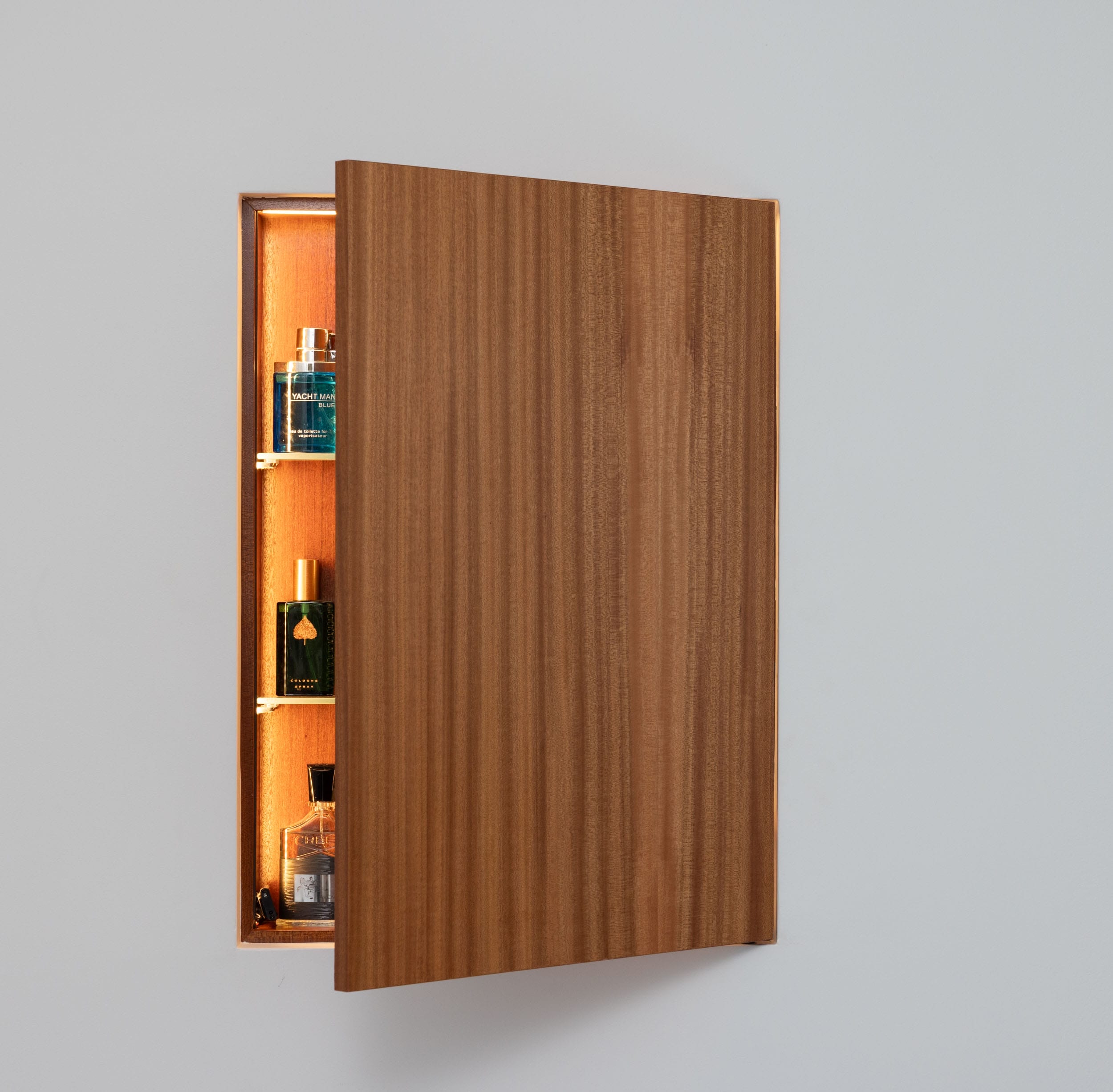 A wooden cabinet with its door partially open reveals shelves containing assorted bottles.