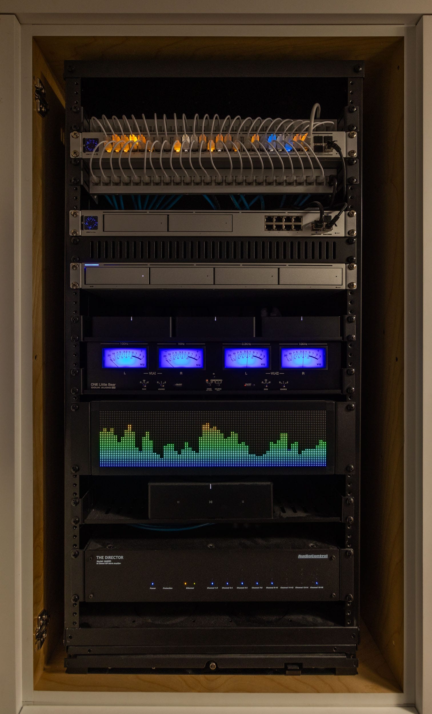 A server rack with illuminated LEDs and various electronic components, including routers and switches, is neatly organized inside a cabinet.