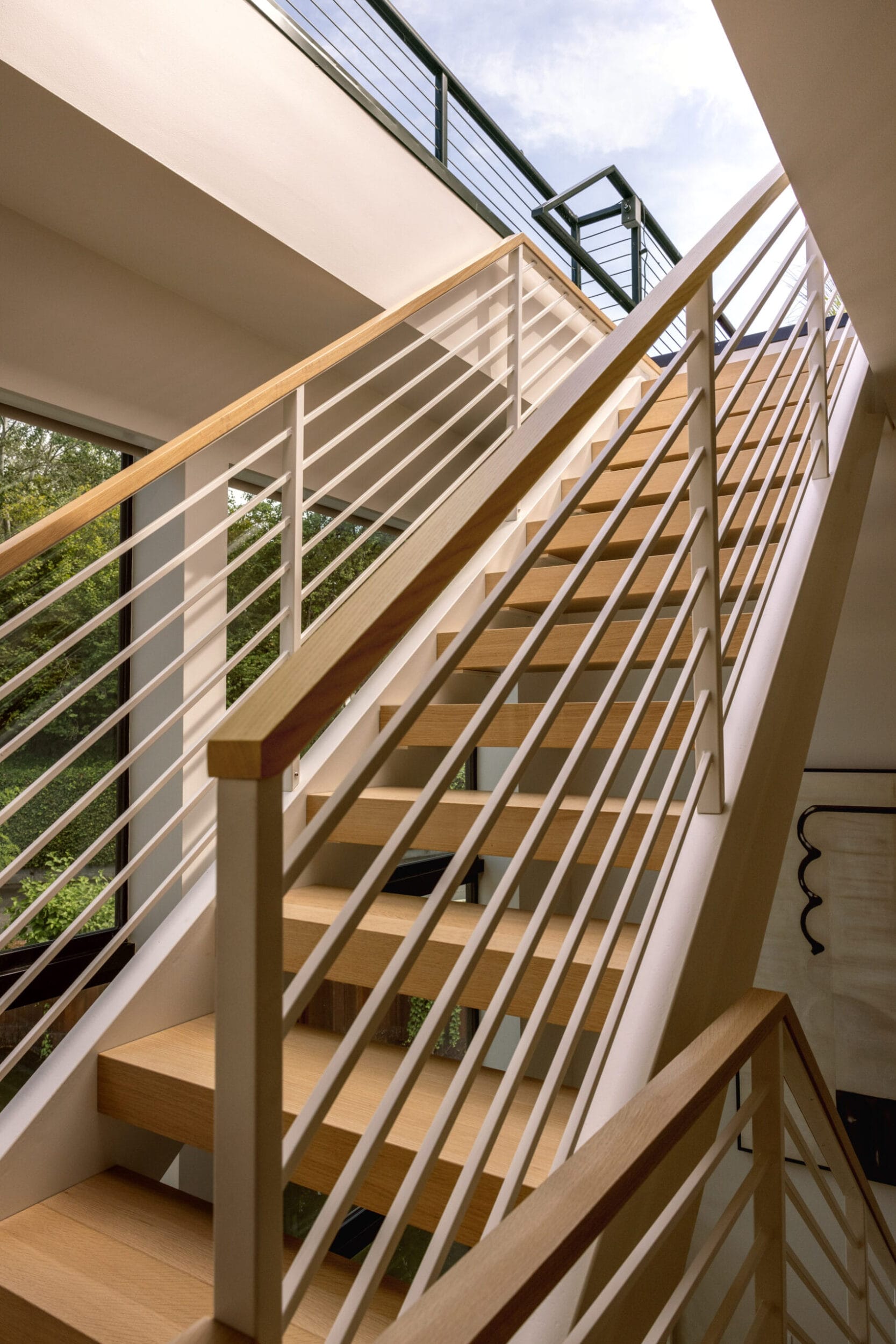 A wooden staircase with metal railings leads upward in a well-lit interior space.